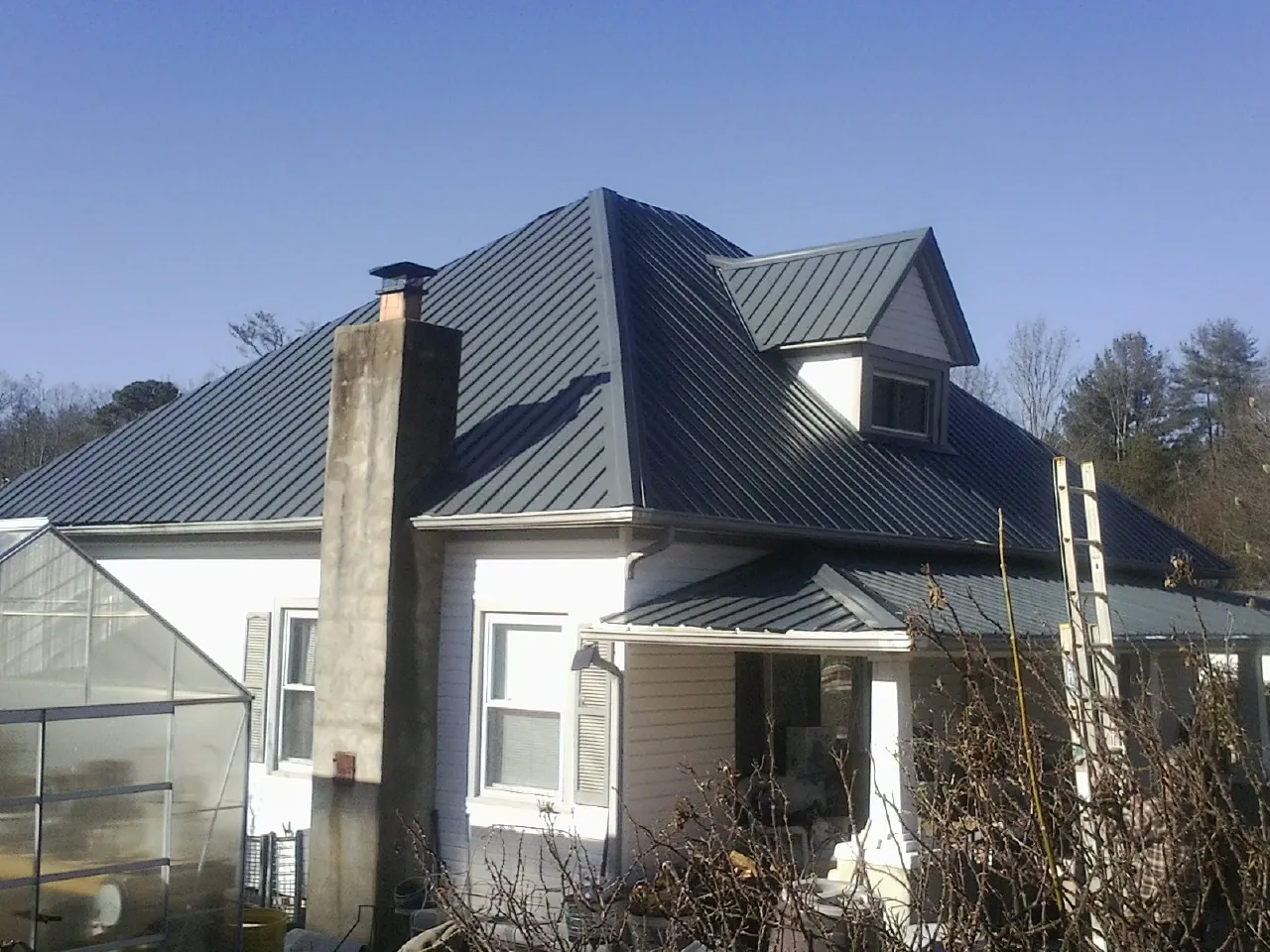 Dark blue standing seam metal roof on a white farmhouse with dormer — Slate & Tile Roof Repair by Roofing Brothers in Forest Knolls
