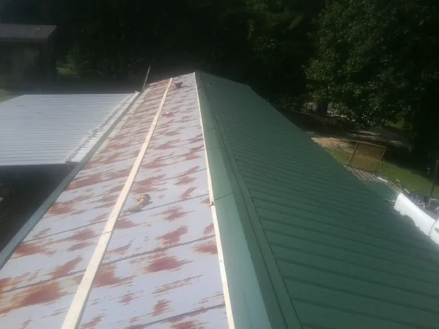 Old rusted panels beside newly installed green metal roofing — Wind Damage Roof Repair by Roofing Brothers in Forest Knolls
