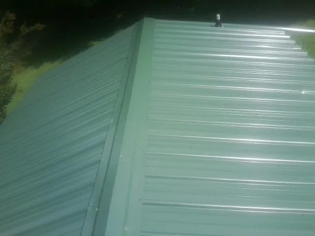 New green metal panels meeting at the ridge of a roof — Flat Roof Repair work by our crew in Forest Knolls