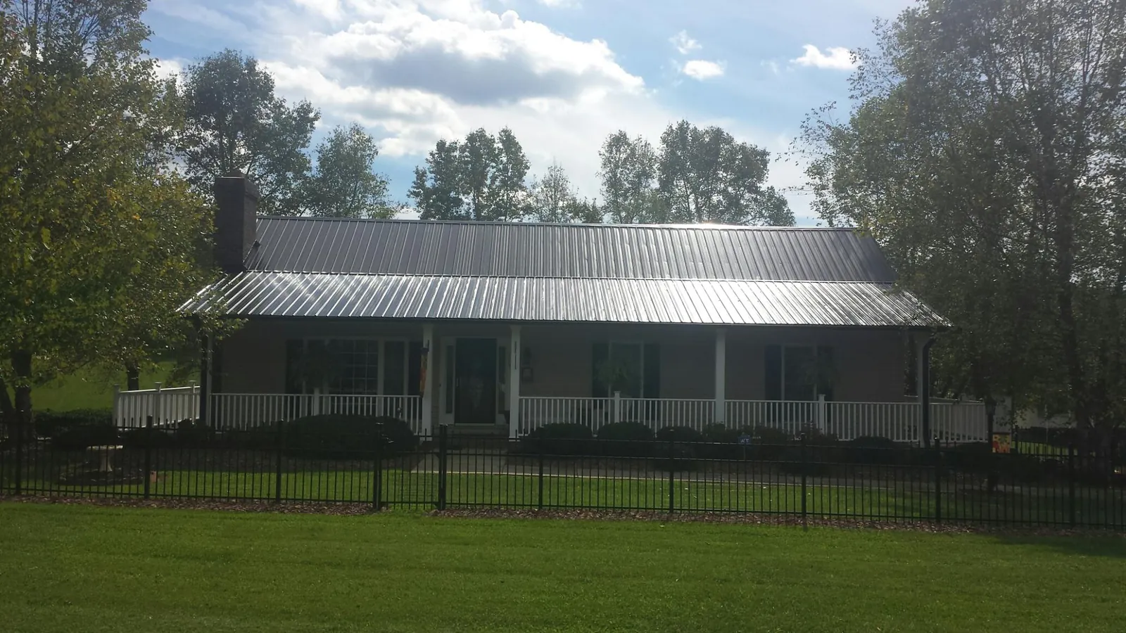 Gray metal roof on a brick ranch with a full width front porch — Gutter Guard Installation work by our crew in Forest Knolls