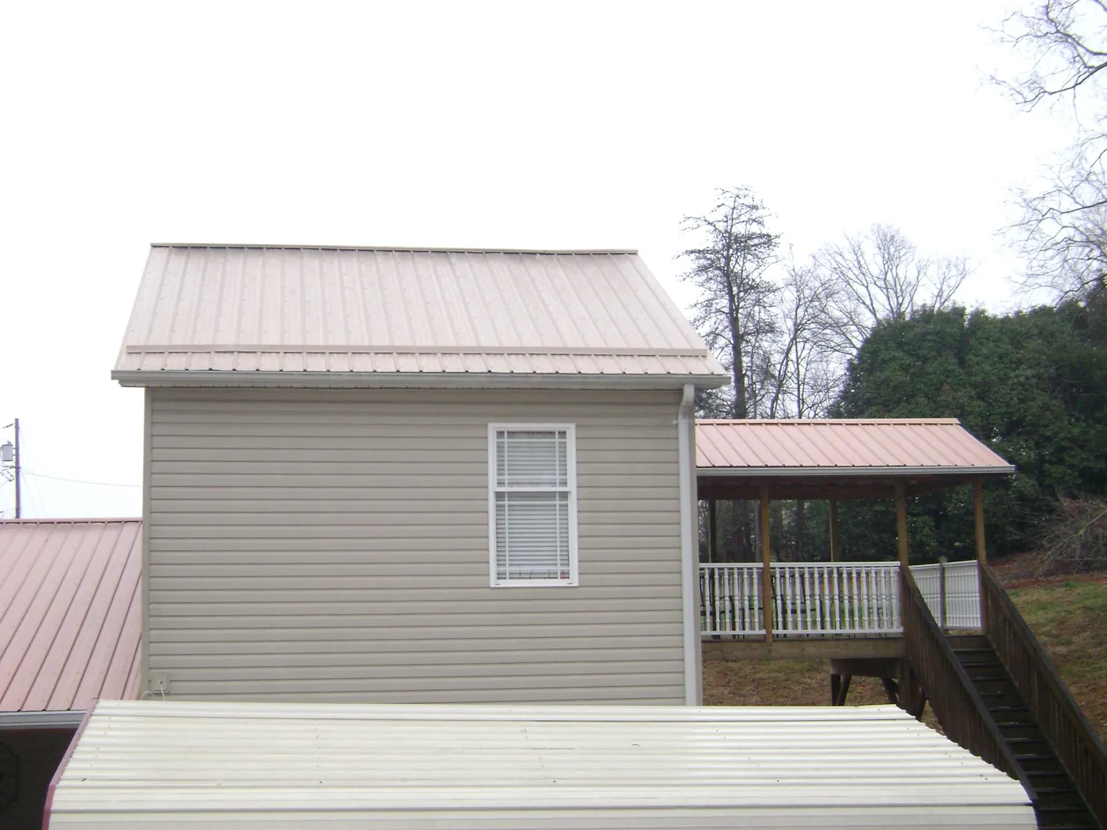 Tan metal roofs on a two story addition and attached porch, from a Roof Replacement job in Forest Knolls