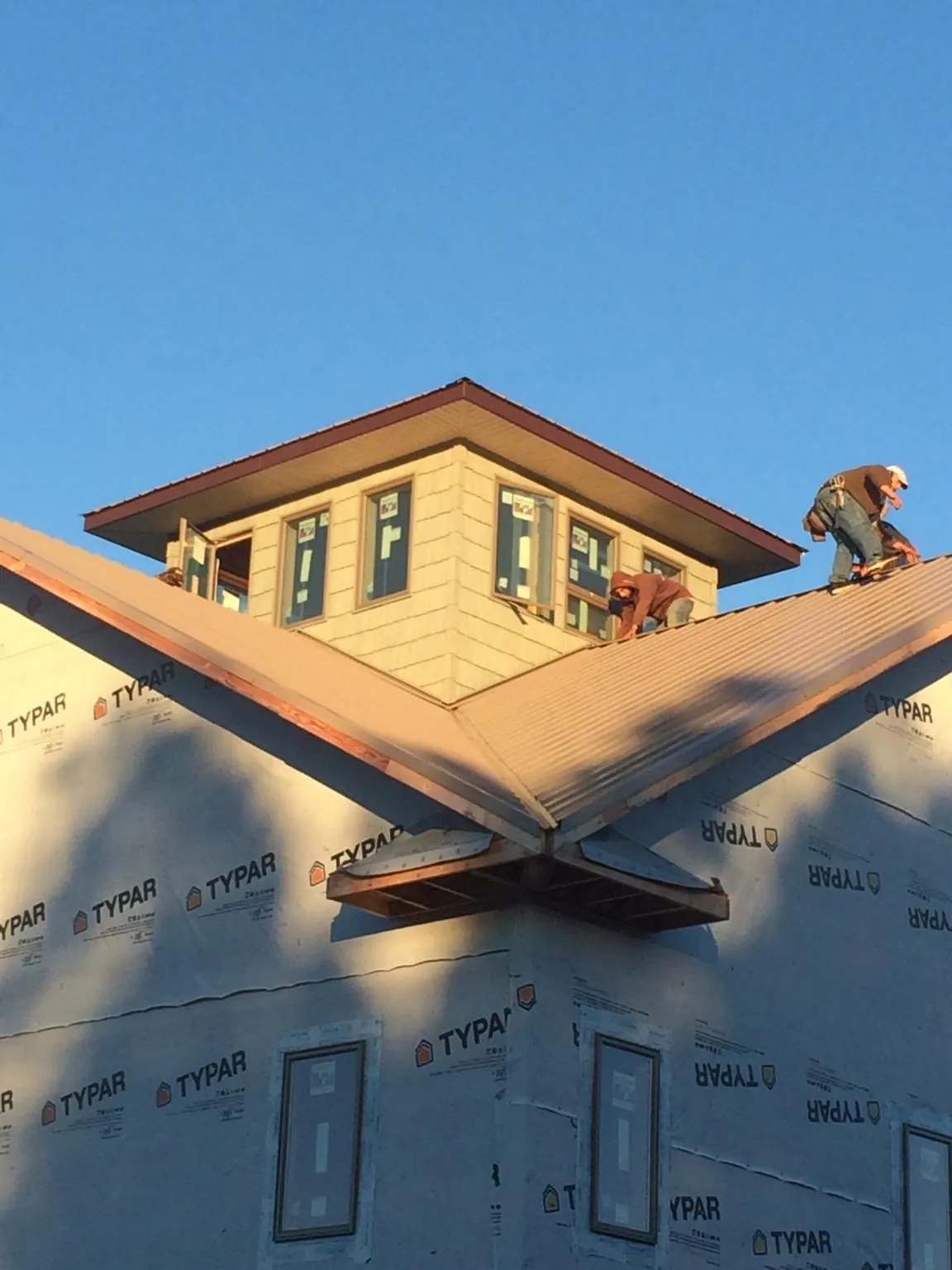 Roofers working around a rooftop cupola on a new metal roof at sunset — Roof Waterproofing in Forest Knolls by Roofing Brothers